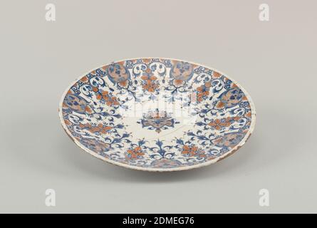 Plate, Tin-glazed thrown earthenware, Circular; lambrequin border and central basket of flowers in terracotta color and blue on white ground., Rouen, France, 1710–30, ceramics, Decorative Arts, Plate Stock Photo