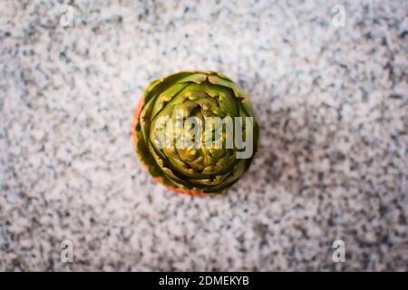 Artichaut vert dans un bol en bois sur un comptoir en granit. Vue de dessus vers le bas. Banque D'Images