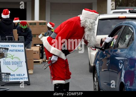 Kingston, États-Unis. 16 décembre 2020. Un père Noël met des canes de bonbons à la disposition d'un client au pantry alimentaire Al Beech.depuis le début de Covid le pantry alimentaire Al Beech a été très occupé, aujourd'hui ils y ont servi un millionième invité. Pour Noël, les bénévoles portaient des chapeaux de père Noël et ont remis des cartes-cadeaux, des bonbons et des ballons avec les produits alimentaires ordinaires. Crédit : SOPA Images Limited/Alamy Live News Banque D'Images