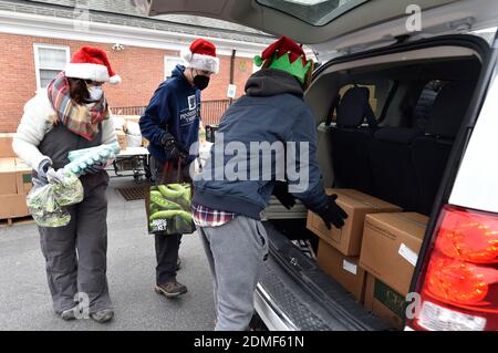 Kingston, États-Unis. 16 décembre 2020. Les volontaires ont mis de la nourriture dans le coffre d'un véhicule à un service sans contact dans le garde-manger.depuis le début de Covid, le garde-manger Al Beech a été très occupé, aujourd'hui ils y ont servi un millionième invité. Pour Noël, les bénévoles portaient des chapeaux de père Noël et ont remis des cartes-cadeaux, des bonbons et des ballons avec les produits alimentaires ordinaires. Crédit : SOPA Images Limited/Alamy Live News Banque D'Images