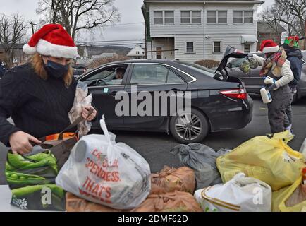 Kingston, États-Unis. 16 décembre 2020. Les volontaires remplissent les voitures avec de la nourriture à un drive dans la banque alimentaire.depuis le début de Covid le pantry alimentaire Al Beech a été très occupé, aujourd'hui ils y ont servi un millionième invité. Pour Noël, les bénévoles portaient des chapeaux de père Noël et ont remis des cartes-cadeaux, des bonbons et des ballons avec les produits alimentaires ordinaires. Crédit : SOPA Images Limited/Alamy Live News Banque D'Images