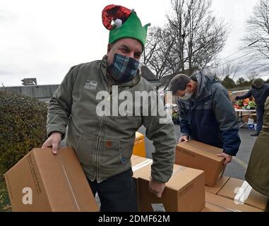 Kingston, United States. 16th Dec, 2020. A volunteer carries boxes of produce to a car at the food bank.Since the start of Covid the Al Beech food pantry has been very busy, today they served there one millionth guest. For Christmas volunteers wore Santa hats and handed out gift cards, candy and balloons along with the regular food goods. Credit: SOPA Images Limited/Alamy Live News Stock Photo