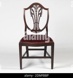 Chaise d'appoint, acajou, dos en forme de bouclier. La splatte verticale ajourée en forme de vase se compose de cinq lamelles verticales incurvées -- le centre est sculpté avec le feuillage à la base; les branches en trois plumes d'autruche. Les épissures des deux côtés courbés vers l'extérieur rencontrent celles de l'extérieur en deux rosettes, d'où pendent des bourgs de drapery. Les pieds avant sont moulés et légèrement coniques. Le rail de siège avant est en serpentin et les rails latéraux sont légèrement couronnés. Il y a une goutte dans le siège recouvert de velours de tissu estampé de soie unie., Angleterre, ca. 1780, meubles, Arts décoratifs, chaise d'appoint Banque D'Images