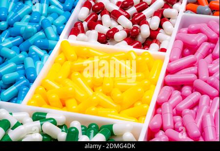 Pilules de capsule multicolores dans une boîte en plastique. Vitamines et suppléments concept. Industrie pharmaceutique. Médicaments d'ordonnance sur plateau en plastique jaune. Banque D'Images