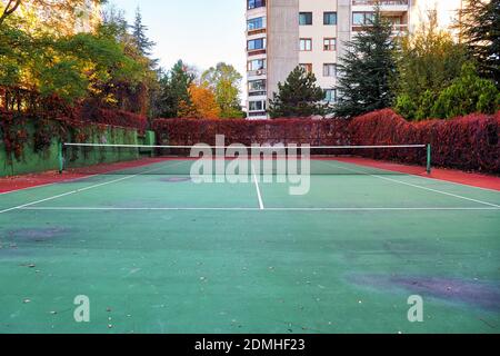 Terrain de tennis extérieur usé en terre battue ou en surface dure avec filet Banque D'Images