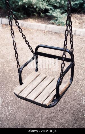 Gros plan balançoire en bois vide vintage avec chaînes suspendues dans un parc d'attractions extérieur pour enfants. Banque D'Images