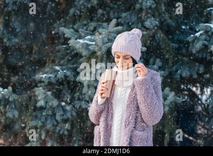 Jeune femme marchant le jour de l'hiver, tenant voyage en acier inoxydable mug avec café chaud. Bouteille d'eau réutilisable. Déchets, réduire, recycler et zéro déchet c Banque D'Images