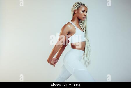 Femme de fitness afro-américaine qui étire les bras pendant l'entraînement. Faites de la femme qui fait de l'entraînement sur fond blanc. Banque D'Images