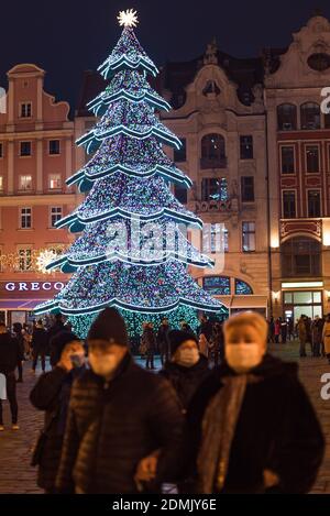 WROCLAW, POLOGNE - 13 DÉCEMBRE 2020 : place du marché de Wroclaw avec arbre de noël illuminé. Les gens portent des masques pour le visage en raison de la pandémie Covid-19. Banque D'Images