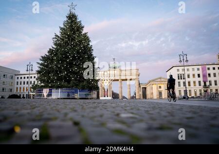 Berlin, Germany. 17th Dec, 2020. A passer-by drives across the still empty Pariser Platz at the Brandenburg Gate in the early morning. Germany is in a hard lockdown to contain the Corona pandemic. Credit: Kay Nietfeld/dpa/Alamy Live News Stock Photo