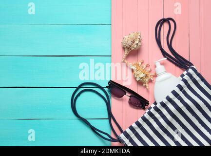 Vêtements et accessoires pour femmes pour se détendre sur la plage sur fond pastel en bois. Sac de plage, pare-soleil, lunettes de soleil, vue du dessus, pose à plat Banque D'Images