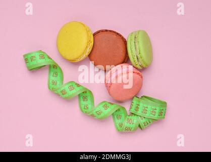 Macarons colorés biscuits et règle sur fond rose pastel. Le concept de perte de poids. Vue de dessus. Banque D'Images