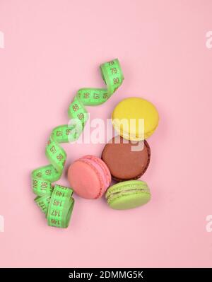 Macarons colorés biscuits et règle sur fond rose pastel. Le concept de perte de poids. Vue de dessus. Banque D'Images