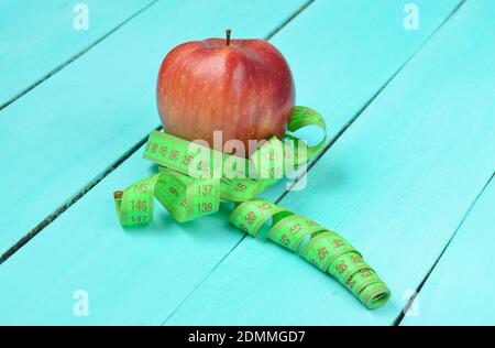 Pomme rouge mûre enveloppée dans une règle sur fond en bois bleu. Banque D'Images