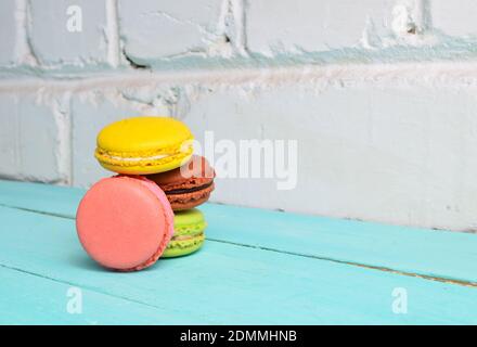 Les macarons de biscuits colorés se rapprochent sur une table contre un blanc arrière-plan du mur de briques Banque D'Images