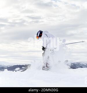 Concept de sports d'hiver. Skieur effectuant des tours dans les montagnes en hiver, en fusion avec le fond. Station de ski à haute heure Banque D'Images