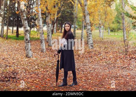 LA JEUNE FEMME ASIATIQUE SE PROMÈNE À TRAVERS LA FORÊT EN AUTOMNE Banque D'Images