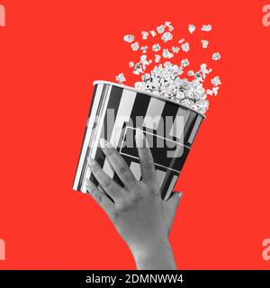Femme tenant main seau à rayures avec pop-corn isolé sur rouge arrière-plan Banque D'Images