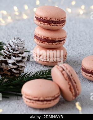 Macarons de figue empilés sur une table blanche, décorés l'hiver avec des branches de sapin et des cônes de pin, un anneau de lumière brille en arrière-plan Banque D'Images