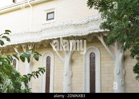 beau bâtiment avec piliers en forme d'arbre. maison en briques jaunes. vitraux de forme ovale. jardin d'été près d'une maison. Banque D'Images