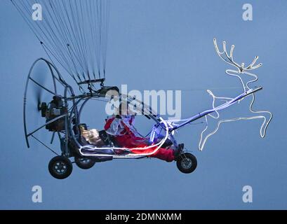 16 décembre 2020, Brandebourg, Francfort (Oder) : un homme en costume du Père Noël survole la campagne sur son tricycle avec un parapente motorisé et un renne illuminé. Comme les années précédentes, l'homme, habillé comme le Père Noël, peut être vu dans le ciel avec sa curieuse machine de vol par beau temps dans la période qui précède Noël. Photo: Patrick Pleul/dpa-Zentralbild/ZB Banque D'Images