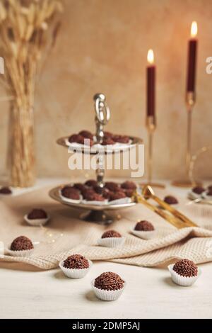 Un cliché vertical de Brigadeiros brésilien, des boules de chocolat sur une plaque à deux couches et des bougies allumées en arrière-plan Banque D'Images