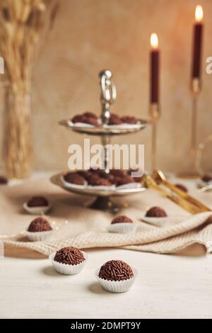 Un cliché vertical de Brigadeiros brésilien, des boules de chocolat sur la table avec des bougies en arrière-plan Banque D'Images