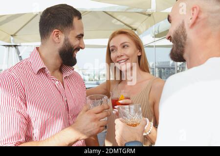 Une belle femme qui parle à ses amis masculins pour prendre un verre une fête sur le toit Banque D'Images