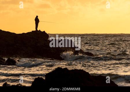 Pêcheur à la mer à Porth Dafarch, Anglesey, au nord du pays de Galles Banque D'Images