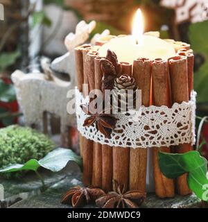 Bougie décorée de bâtons de cannelle, de mousse, de feuilles de lierre et de bois de déers - magnifique arrangement naturel de Noël. Banque D'Images