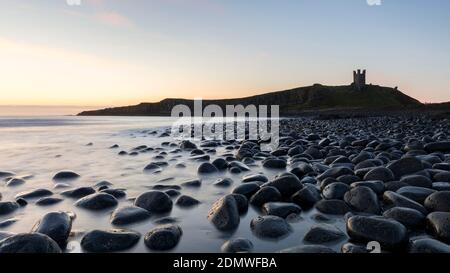 Lever du soleil, Château de Dunstanburgh depuis la baie d'Embleton, côte de Northumberland Banque D'Images