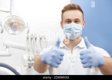 Toujours professionnel ! Dentiste professionnel portant un masque de protection et des gants montrant les pouces de poser à sa clinique dentaire copyspace professionnalisme g Banque D'Images