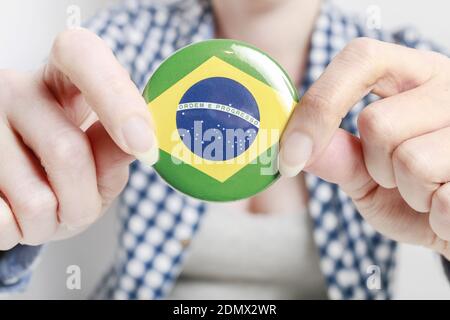 Drapeau du Brésil imprimé sur le badge de bouton, tenu par une femme dans ses belles mains. Banque D'Images