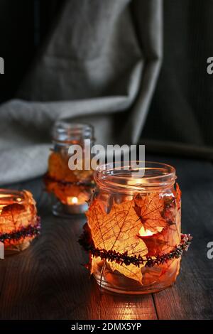 Lanterne d'automne faite d'un pot en verre décoré de feuilles colorées et d'une couronne de bruyère. Bougie à l'intérieur. Banque D'Images