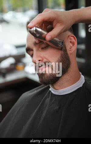 Gros plan vertical d'un homme dont la barbe est taillée par barbier professionnel Banque D'Images