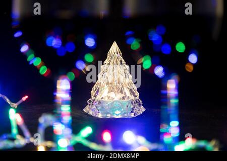 Un sapin de Noël brillant en cristal se dresse derrière deux verres à vin dans un flou entouré d'une guirlande brillante. Gros plan, mise au point douce... Banque D'Images