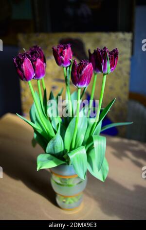 Bouquet de tulipes violettes fraîches dans vase en verre, fleurs magnifiquement illuminées par la lumière du soleil, arrière-plan flou Banque D'Images