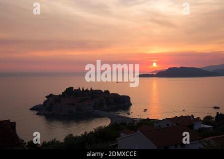 Sveti Stefan, Budva, Monténégro. Vue sur les eaux tranquilles de la baie de Budva et la station balnéaire exclusive de Sveti Stefan, coucher de soleil. Banque D'Images