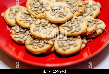 Gros plan de biscuits faits maison avec graines de tournesol empilées dans une assiette rouge Banque D'Images