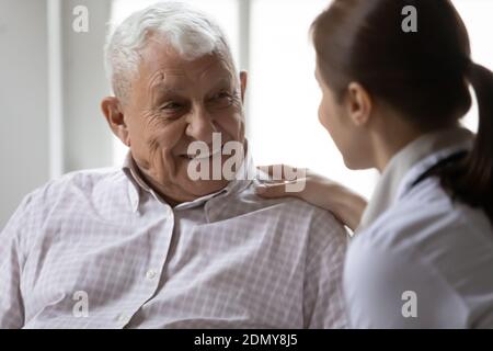 Jeune femme fréquentant un médecin s'occupant d'un patient âgé de la clinique avec sympathie Banque D'Images