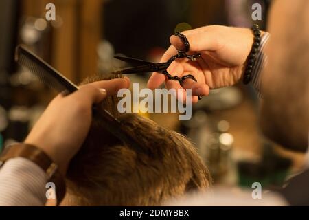 Petit gros plan des mains d'un coiffeur professionnel donner une coupe de cheveux à son coiffeur de coiffeur de client masculin métier barbershop barbering Banque D'Images