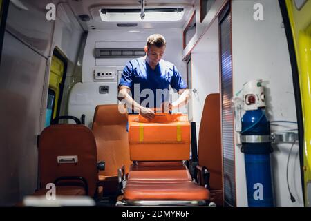 Jeune médecin préparant son kit médical dans la voiture d'ambulance. Banque D'Images