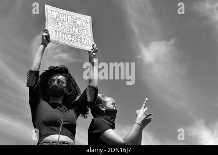 Les vies noires sont importantes en noir et blanc - une femme avec un masque tenant un écriteau sur sa tête et une autre femme prenant une photo avec son téléphone. Banque D'Images