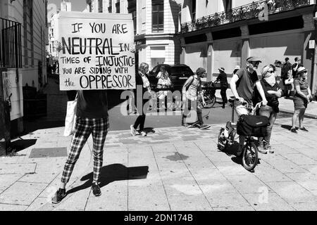 Le noir est important en noir et blanc - femme tenant un écriteau et d'autres personnes qui regardent la manifestation Banque D'Images