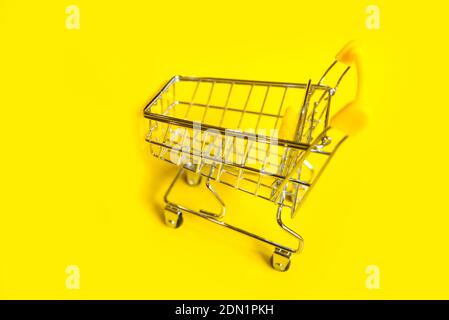 an empty shopping cart on a bright yellow background. Stock Photo