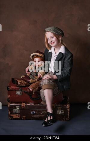 portrait vintage d'une petite fille. enfant assis sur des valises avec un petit garçon jouet Banque D'Images