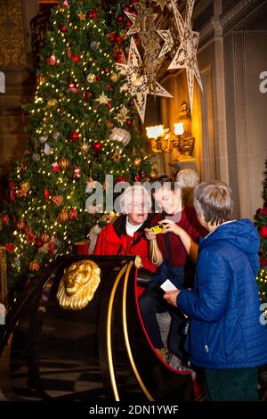 UK, England, Derbyshire, Edensor, Chatsworth House Painted Hall at Christmas, Lands Far Away, Russia, woman posing on sleigh being shown picture on di Stock Photo