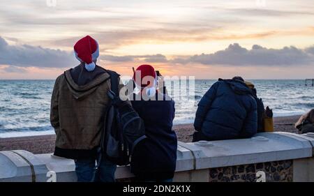 Brighton Royaume-Uni 17 décembre 2020 - UN couple à Santa Hats profiter du coucher de soleil sur le front de mer de Brighton à la fin d'une journée lumineuse sur la côte sud . La ville de Brighton et Hove a été maintenue dans les restrictions de niveau deux de coronavirus en Angleterre après une annonce plus tôt aujourd'hui par le secrétaire à la Santé Matt Hancock : crédit Simon Dack / Alamy Live News Banque D'Images