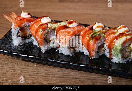 Sushi farci de crevettes recouvertes de saumon et d'avocat. Banque D'Images