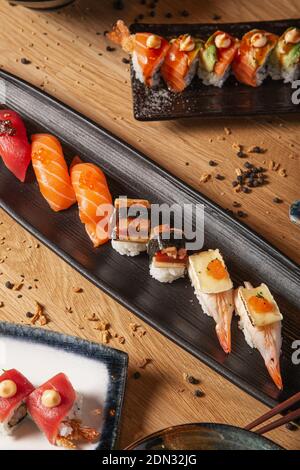 Variété de sushis et de nigiri servis sur la table dans des assiettes en céramique. Banque D'Images